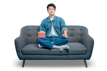 PNG,A relaxed young man in casual attire sits on a sofa holding a bucket of popcorn, ready for a...