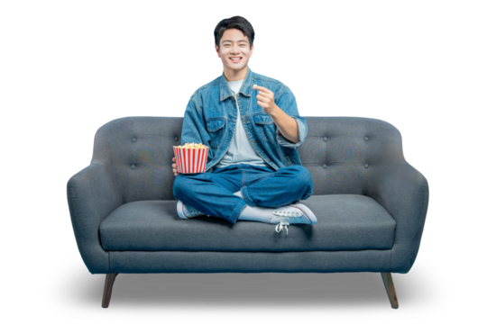 PNG,A friendly man on a sofa holds popcorn and makes a Korean finger heart gesture, showing love for a movie or show.
