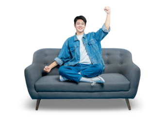 A young man on a sofa celebrates with a fist pump gesture, cheering for his favorite team or a movie hero.PNG
