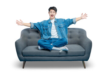 An excited young man sits on a sofa with his arms open wide in a joyful and welcoming gesture.PNG