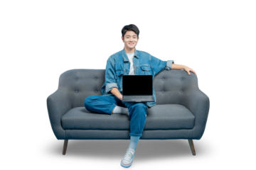 A relaxed young man sits on a sofa with a laptop on his lap, smiling at the camera, perfect for remote work or e-learning concepts.PNG