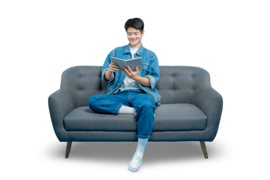 A young man sits comfortably on a sofa, smiling as he reads a book, representing leisure, study, and learning.PNG