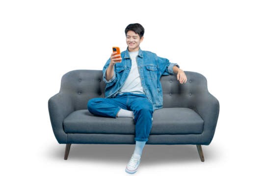 A relaxed young man in casual attire sits on a sofa and smiles while using his smartphone.PNG