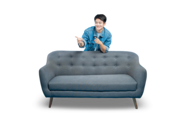 A young man peeks from behind a sofa and points, as if showing a surprising deal or message.PNG