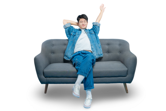 A cheerful young man relaxes on a sofa with his hands behind his head and gives a friendly wave.PNG