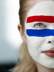 A bold face paint with colors of flag of Netherlands symbolizes national pride and identity...