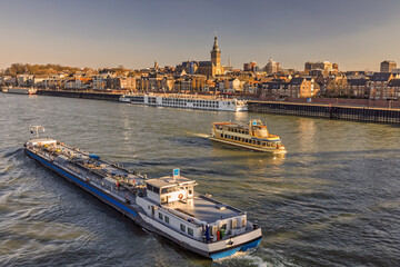 Panoramic view of the Dutch city of Nijmegen during sunset with the river Waal and boats in front