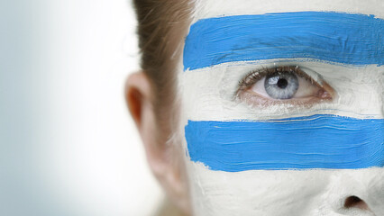 A close-up of face paint with bold blue stripes represents national pride and civic identity....