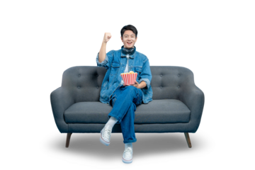 A young man watching a movie on the sofa celebrates with a fist pump, excited by a triumphant scene or a sports game victory.PNG