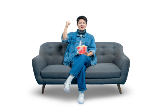 A young man watching a movie on the sofa celebrates with a fist pump, excited by a triumphant scene or a sports game victory.PNG - Powered by Adobe
