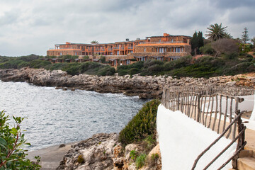 Background with stone beautiful residential houses on the seashore among the cliffs of Menorca,...
