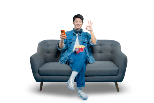 A happy man on a sofa holds a phone and gives an "OK" gesture, indicating satisfaction with a mobile app or streaming service.PNG