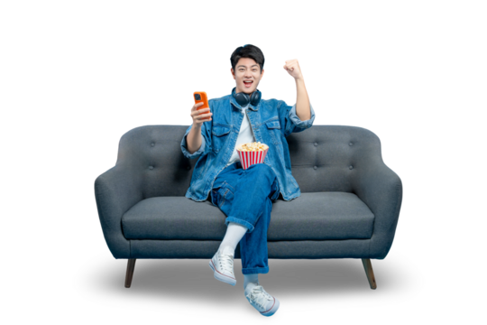 An excited young man with popcorn holds a smartphone and cheers, celebrating a win in a mobile game or seeing great news , PNG