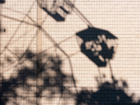 Shadow of people in a ferris wheel on a building wall
