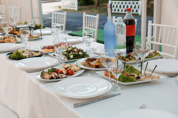 Elegant Wedding Reception Table Setting with Gourmet Food, Wine, and White Decor, Garden View and Soft Lighting