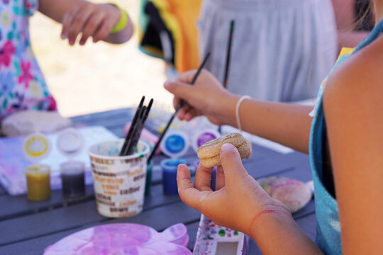 vacations and children's activities. children doing outdoor arts and crafts painting stones.