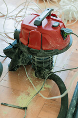 Red Shop Vacuum Cleaner in Home Renovation Scene with Debris. Dust, Tools, Wooden Flooring,...
