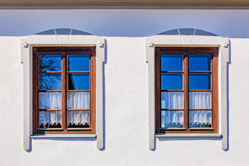 Charming wooden windows with lace curtains on white wall