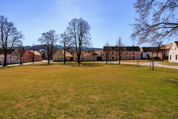 Charming european village square with historic houses and trees on a sunny day