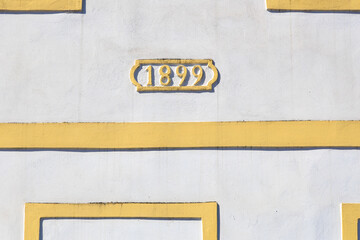Architectural detail with 1899 date on yellow and white building facade