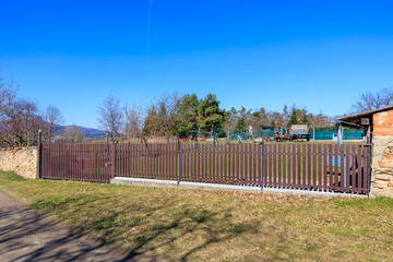 Rural landscape with metal fence and open field under clear blue sky