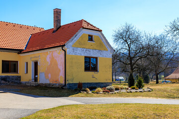 Charming rural cottage with red roof and weathered yellow walls in countryside landscape