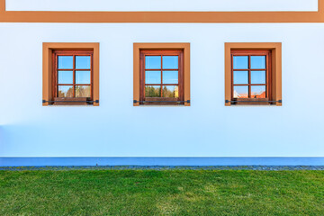 Symmetrical triple windows on white building with green grass lawn