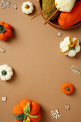 Cozy autumn basket with crocheted pumpkins and yarn on a brown background. Perfect for seasonal crafts, DIY projects, and rustic lifestyle visuals