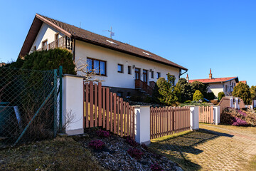Suburban house with wooden fence and garden under clear blue sky