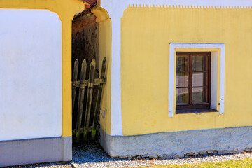 Yellow wall with window and rustic fence in sunlit scene