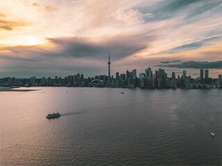 Naklejka premium Toronto skyline at sunset with a ferry on Lake Ontario.