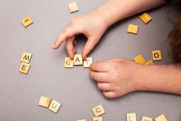 child hand hands collecting word cat from wooden cubes on gray background.