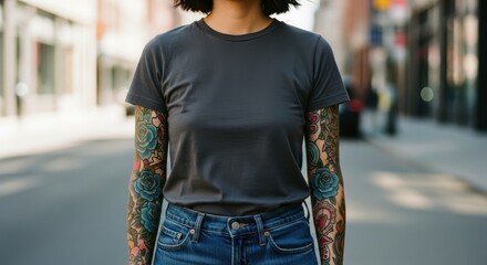 Woman in plain grey t shirt with full sleeve tattoos standing on city street