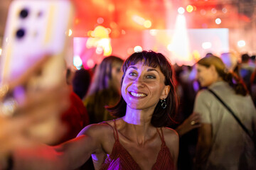 Girl at a concert. A cheerful and happy girl takes a selfie on her phone at a summer music festival.