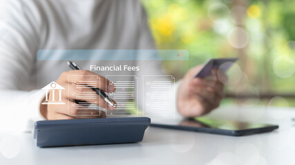 Person calculating financial fees using a calculator and holding a credit card, representing online...