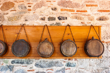 Row of traditional wooden canteens hanging on chains against stone monastery wall