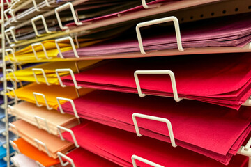 stacks of colorful craft paper arranged neatly on a metal shelf rack in an art supply store