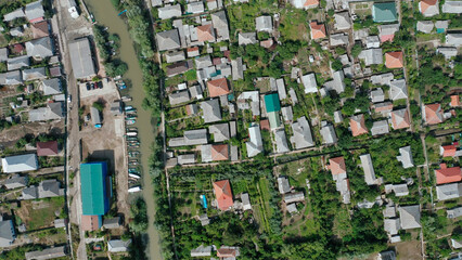 Aerial view of a suburban neighborhood with houses, gardens, and a small canal with docked boats,...