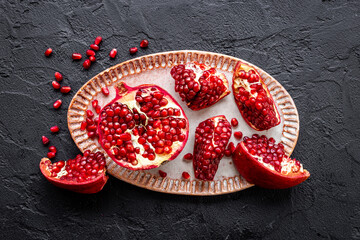 Top view of fresh ripe pomegranate and pieces on plate for eating, top view.