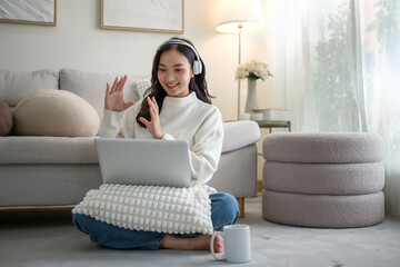 Cheerful female wearing headphones having an online meeting from home.
