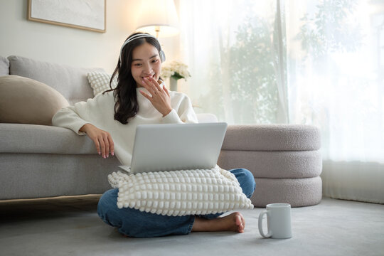Surprised young woman covering her mouth while discovering unexpected news on her laptop at home. - Powered by Adobe