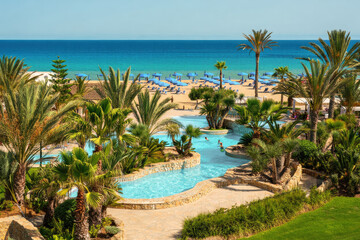 A beautiful resort with a pool overlooking a stunning beach and the ocean.
