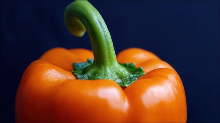 Close-up of orange bell pepper with fresh green stem, vibrant colors against dark blue background, crisp details, natural lighting