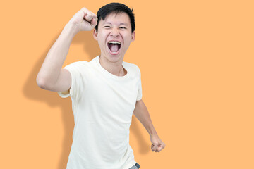 A young Asian man with braces, wearing a white t-shirt, celebrates fists and a smile against an...