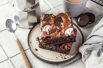 Homemade chocolate brownie cake with cookies with coffee on a plate on gray tile background