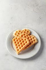 Heart shaped waffles on white ceramic plate isolated on gray background