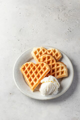 Heart shaped waffles with ice cream scope on white ceramic plate isolated on gray background