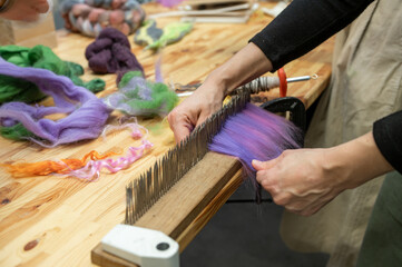 Hands preparing wool for crafting on hackle with colorful fibers