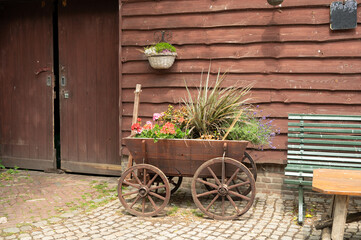 Rustic wooden cart with colorful flowers by vintage barn
