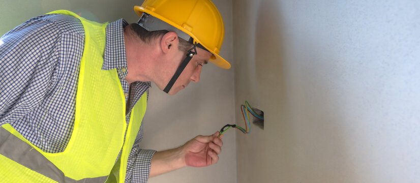 Male electrician inspecting wire cable on wall outlet